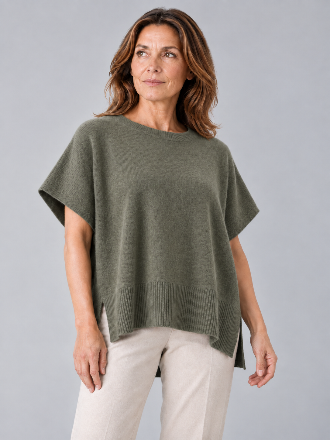 siggy-cashmere-mix-jumper-fir-green-colour-front-view-model - Ochre Knitwear cashmere mix jumper, sleeveless in fir green colour with side split, presented by middle age model and white trousers