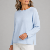 Older woman with shoulder-length gray hair in a light blue knit sweater with long sleeves