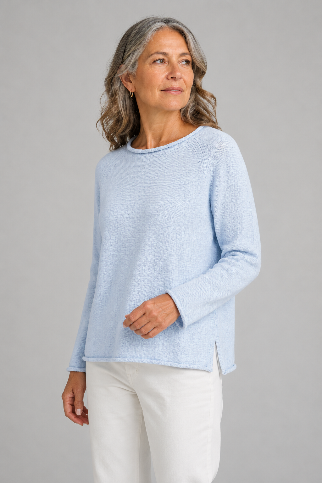 Older woman with shoulder-length gray hair in a light blue knit sweater with long sleeves