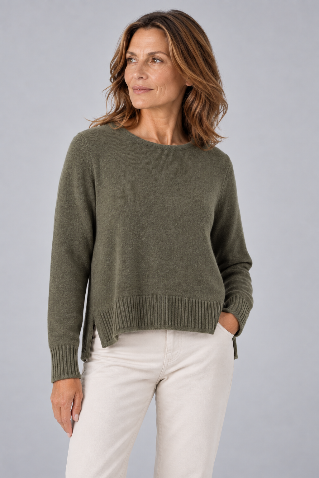 sweater with long sleeves, longer at the back and side slits in green colour, front view presented by brunette middle age model