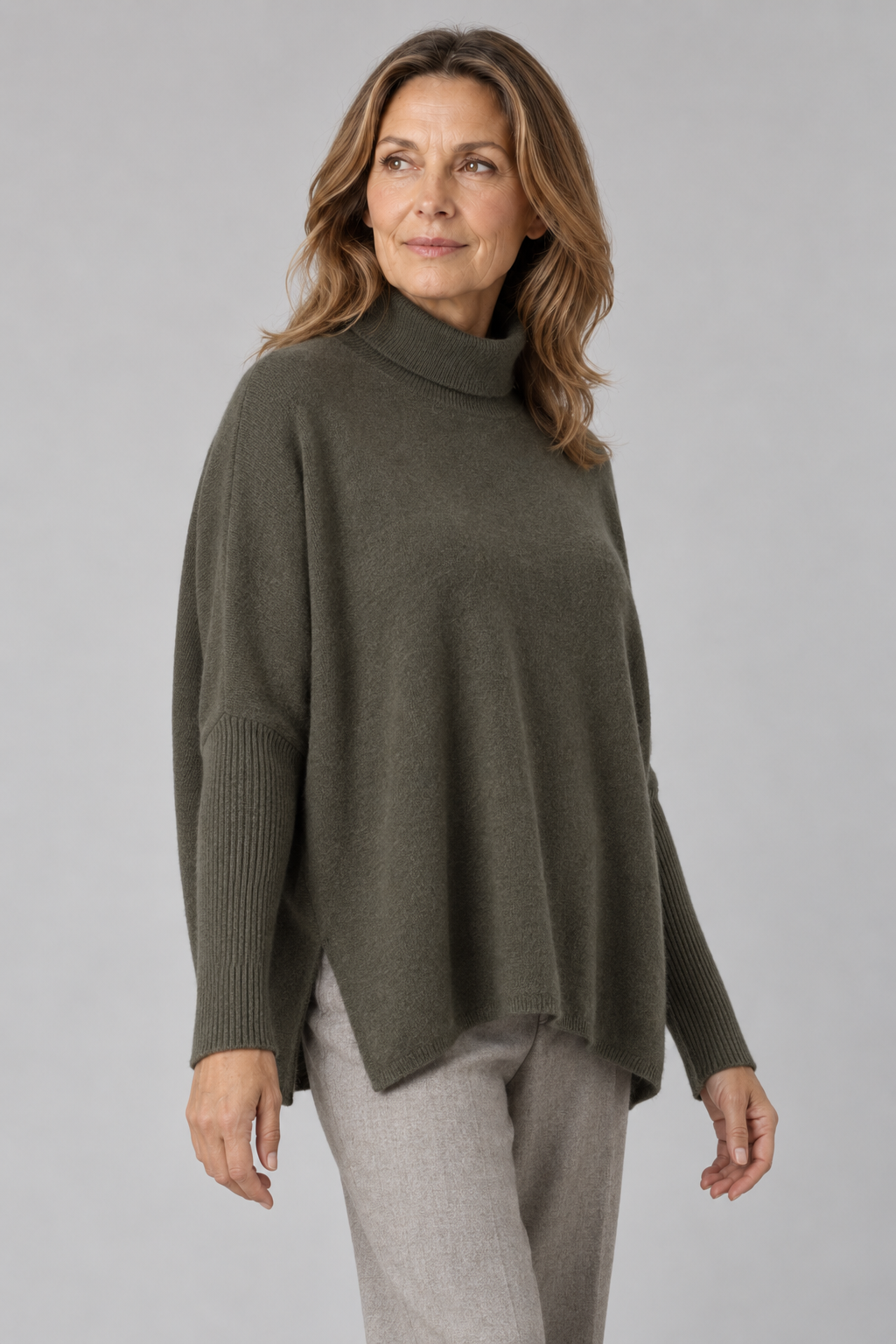 Torvi-polo-neck-jumper-fir-green-colour-front-model - Ochre Knitwear polo neck jumper in fir green colour with slit opening and long sleeves, front view presented by brunette middle age model wearing grey trousers