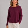 Model wearing a burgundy boat neck cashmere lambswool jumper with relaxed square shape, long sleeves and soft rolled hem finish.