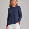 Older woman with gray hair wearing a navy knit sweater and white pants, looking to the right.