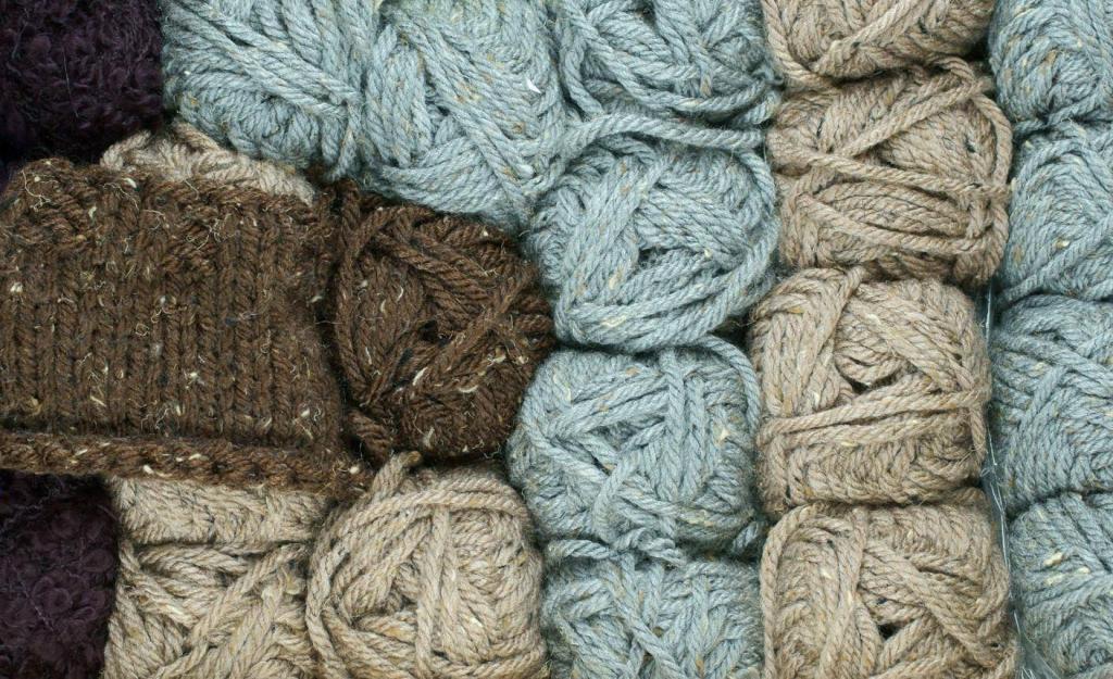 Assorted skeins of chunky rope yarn in brown, blue-gray, and beige piled together on a flat surface.