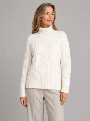 enya-aran-roll-neck-jumper-ivory-colour-front-model aran roll neck jumper with high ribbed collar, raised cable panels, diamond stitch detail and deep ribbed hem, front view, presented by model