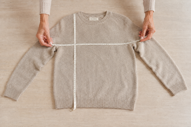 Oatmeal natural-fibre jumper laid flat with measuring tape across the chest and from shoulder to hem