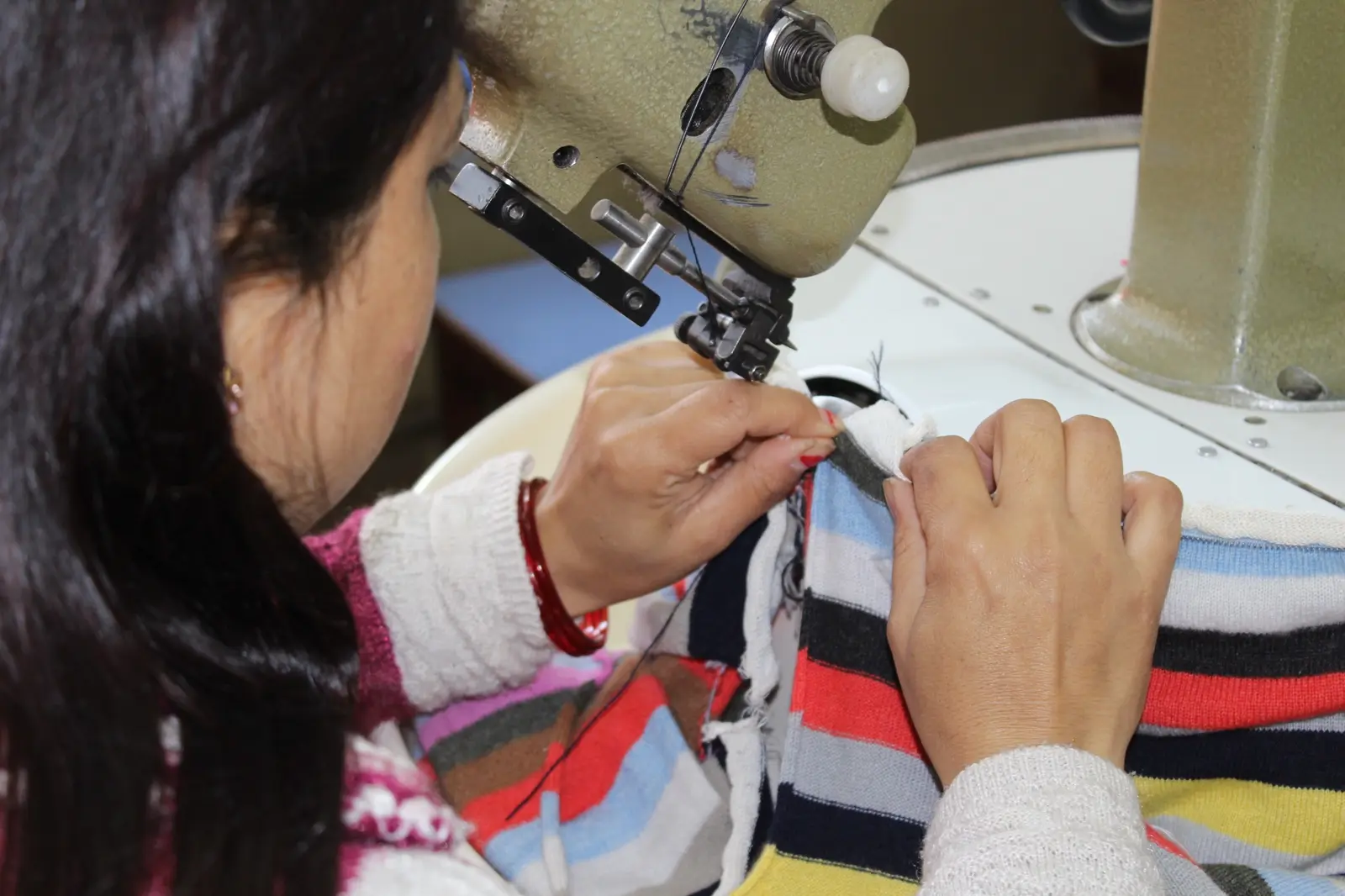 Skilled Ochre craftsperson linking a knitted garment in Kathmandu