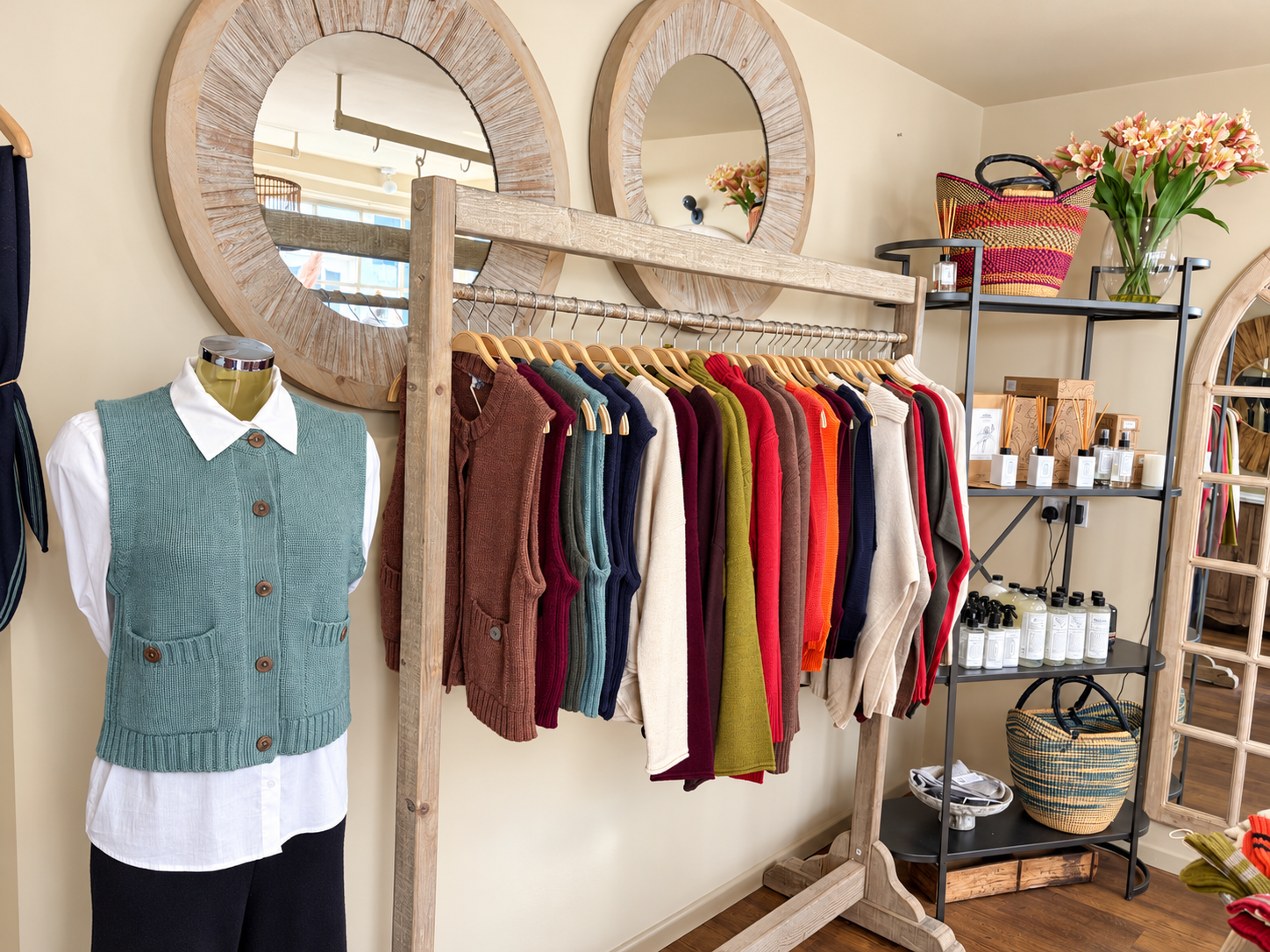 Colourful knitwear on a wooden rail beside a teal buttoned vest at Ochre’s knitwear shop in Dartmouth.