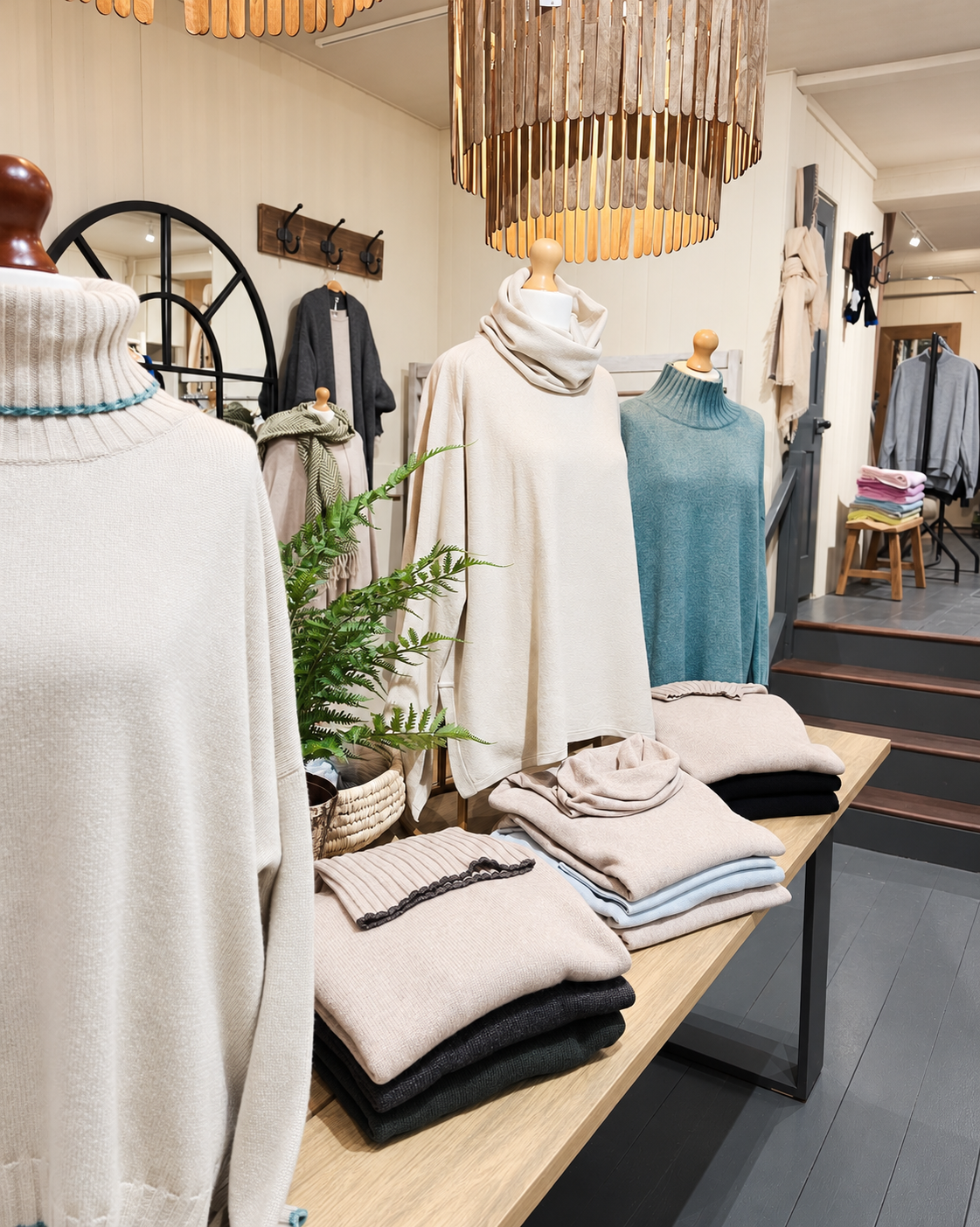 Mannequins wearing cream and teal knitwear beside neatly folded jumpers at Ochre’s knitwear shop in Arundel.