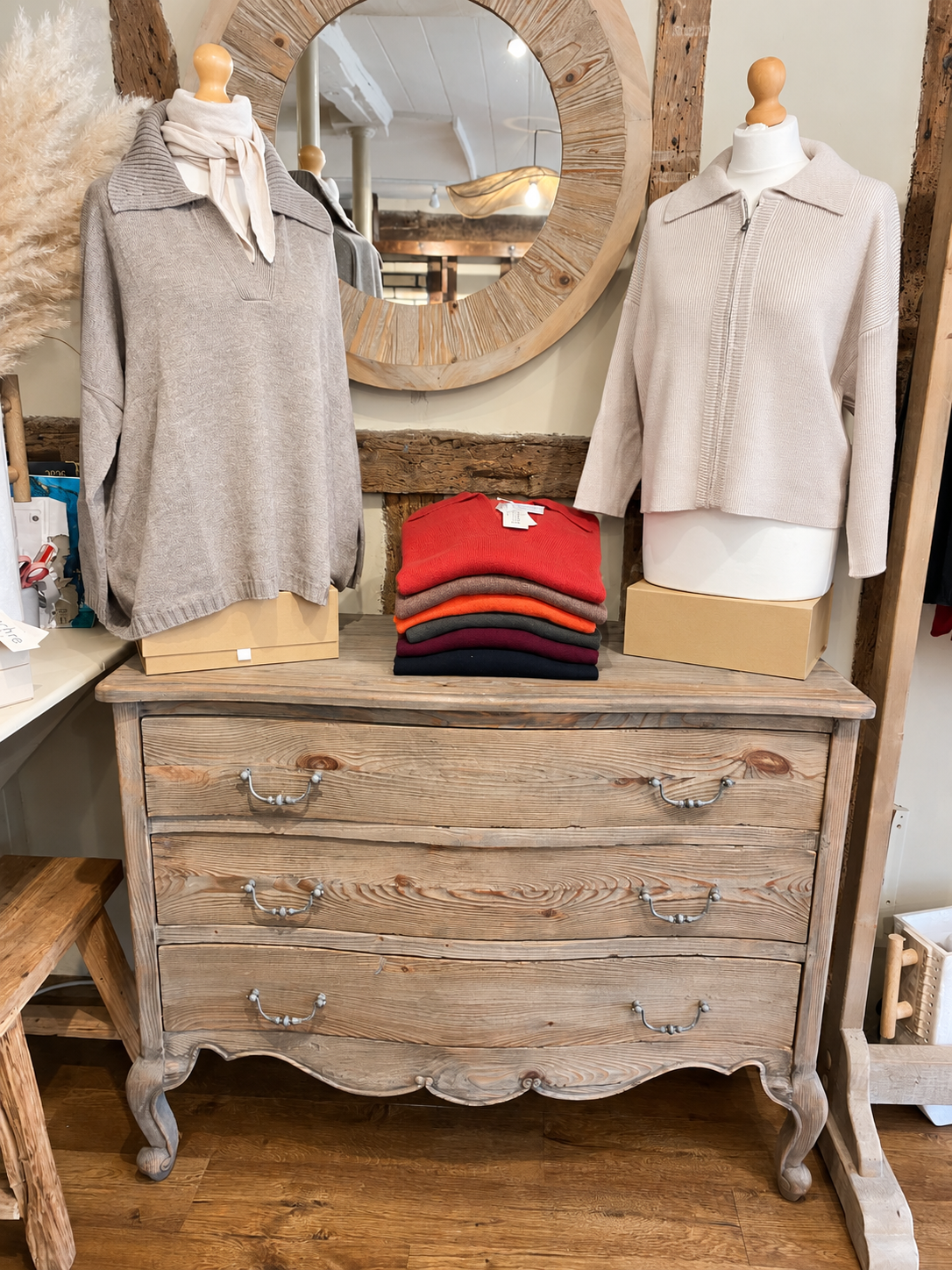 Pale jumpers on mannequins beside folded knitwear on a wooden chest at Ochre’s knitwear shop in Lewes.