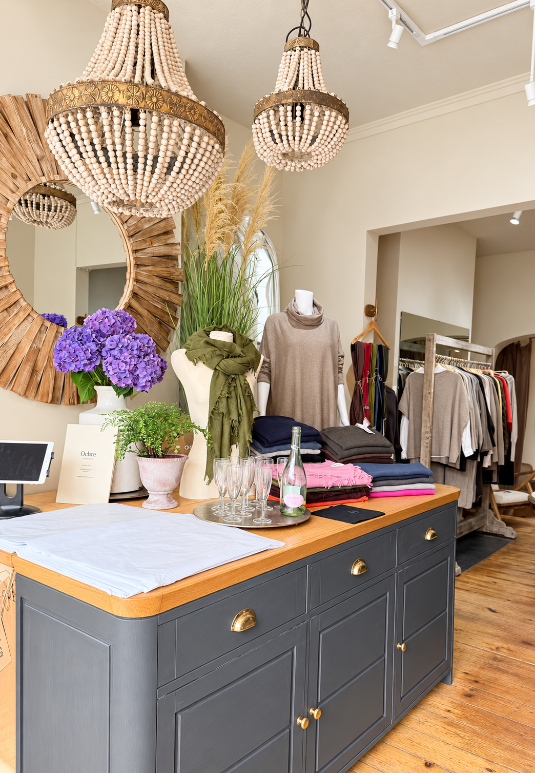 Folded knitwear and scarves beside purple hydrangeas on the counter at Ochre’s knitwear shop in Lymington.