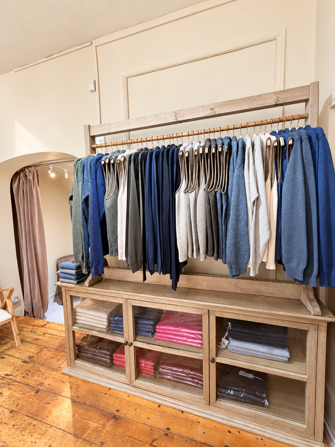 Neutral men's jumpers on a wooden display table at Ochre’s knitwear shop in Lymington.